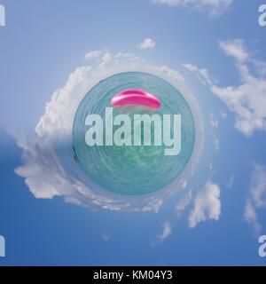 A pink floating tire floating on the indian ocean from a tiny world perspective Stock Photo