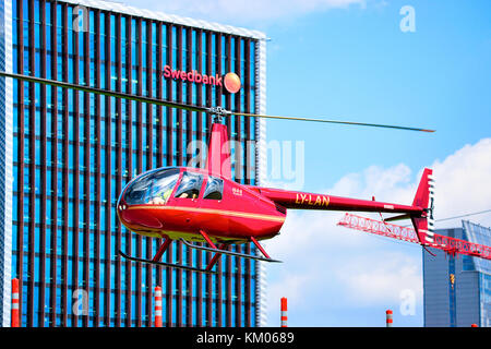 Vilnius, Lithuania - May 6, 2017: Red helicopter flying at Office of Swedbank in modern skyscraper in downtown of Vilnius, Lithuania Stock Photo