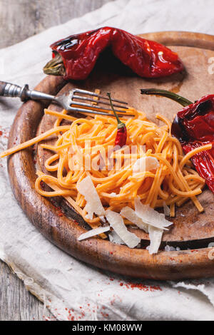 Orange tomato spaghett (tagliolini al pomodoro) with grilled red paprika and cheese parmesan served on wooden cutting board Stock Photo