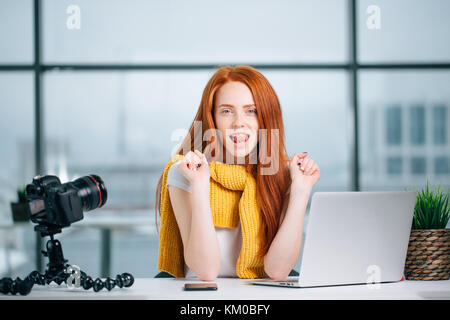 Young woman working on computer with cameras and accessories on table. Stock Photo