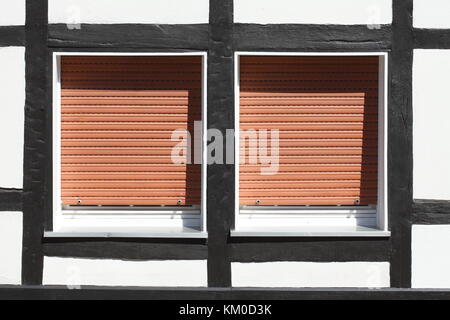 White Plastic Windows on a half-timbered house with  pulled down shutters Stock Photo