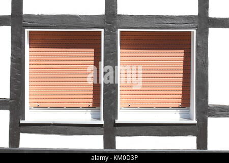 White Plastic Windows on a half-timbered house with  pulled down shutters Stock Photo