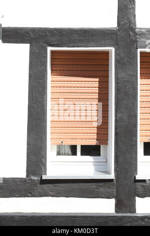 White Plastic Windows on a half-timbered house with  pulled down shutters Stock Photo