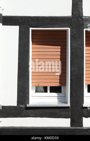 White Plastic Windows on a half-timbered house with  pulled down shutters Stock Photo