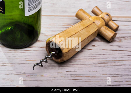 Old, retro wooden corkscrew, on distressed wooden table with empty wine bottle. Stock Photo