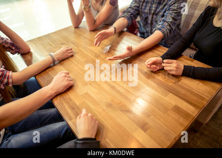 Group of students sitting in a cafe bar looking at each other Stock Photo