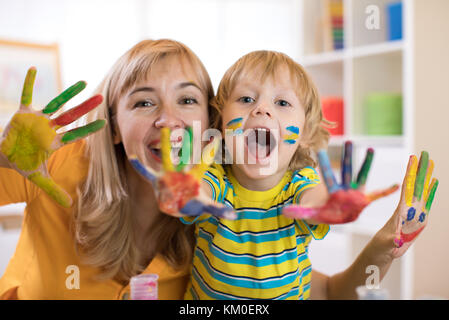 Smiling child boy and his mother having fun and showing hands painted in colorful paints Stock Photo