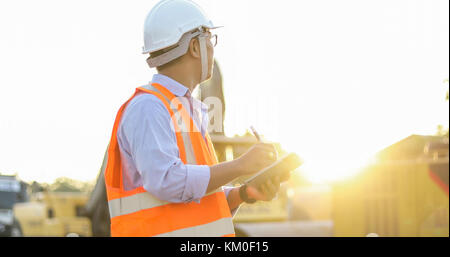 Asian engineer with hardhat using  tablet pc computer inspecting and working at construction site Stock Photo