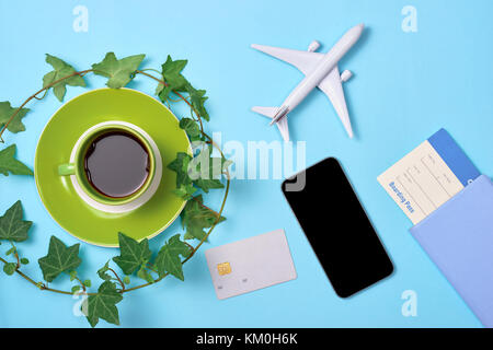 Top view of desk with smartphone, coffee cup, passport, plane model and credit card. Stock Photo