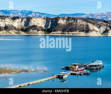 long, wooden pier surrounded by boats at California's Lake Cachuma near Los Padres National Forest with San Rafael Mountains in the distance Stock Photo