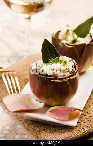 Stuffed artichokes with risotto on elegant table with golden fork Stock Photo