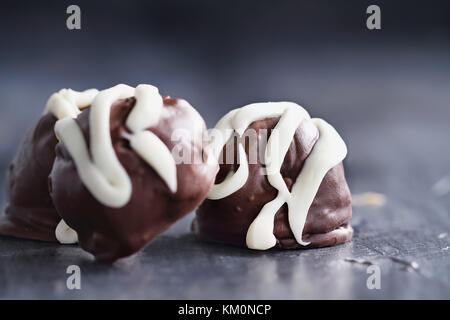 Dark Chocolate truffles for Christmas or Valentines's Day drizzled with white chocolate. Extreme shallow depth of field with selective focus on candy  Stock Photo