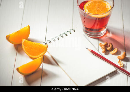 Cup of hot christmas drink. Mulled wine with orange and notebook with copyspace. Stock Photo