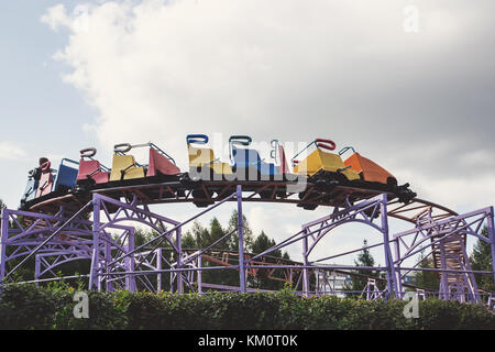 train goes up the stairs to the rides in the amusement Park against the sky Stock Photo