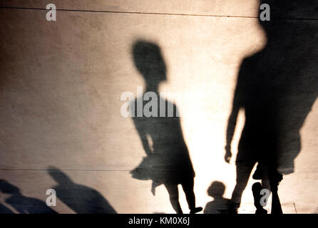 Blurry shadows silhouettes of people walking on misty summer promenade Stock Photo