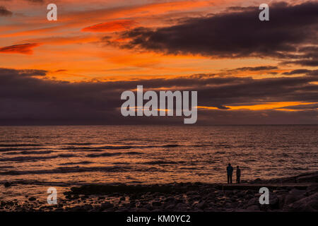 Two People on the coast watching a sunset at Llantwit Major beach, Glamorgan Heritage Coast Stock Photo