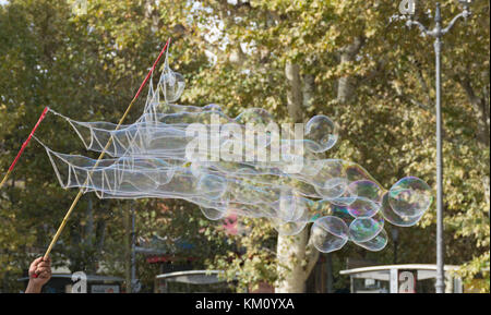 Blowing multiple iridescent round bubbles with soap, water, bamboo sticks and string. Stock Photo
