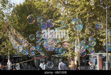 Multiple beautiful iridescent bubbles made with soap, water and air at a pedestrian mall.  Photographed with a shallow depth of field. Stock Photo