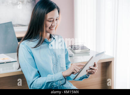 Asian businesswoman use tablet to online conference meeting with smiling face,Happy office life concept,working woman at modern home office. Stock Photo