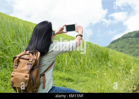 Asia woman traveler with backpack use mobile phone take a photo of landscape mountain view,Travel wanderlust concept,mock up screen mobile Stock Photo