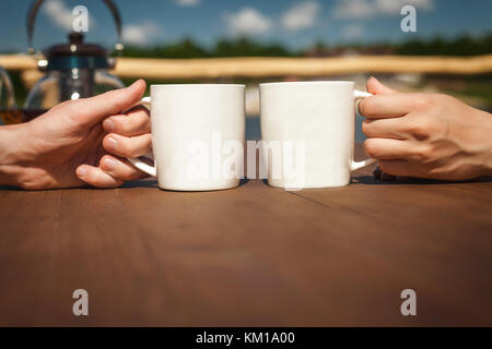 boy and girl resting and drinking tea near lake on terrace Stock Photo