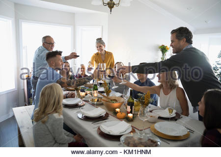 Family and friends toasting champagne and wine glasses at Thanksgiving dinner table