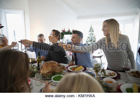 Family and friends toasting champagne glasses at turkey Christmas dinner table