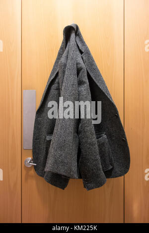Tweed jacket hung up on the inside of a toilet cubicle door Stock Photo