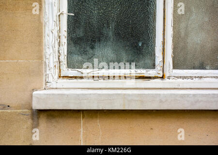 Peeling paint on an old window with frosted privacy glass Stock Photo