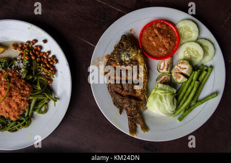 Indonesian food: Kankung plecing (spicy water spinach dish) and Ikan goreng (fried fish) top view Stock Photo