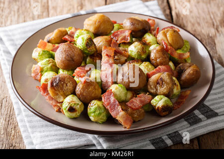 Delicious appetizer: roasted chestnuts, Brussels sprouts and bacon close-up on a plate on a table. horizontal Stock Photo