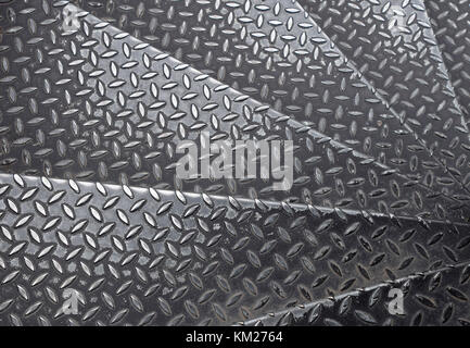 Black painted industrial anti slip embossed metal steel plate steps of staircase with diagonal bumps of diamond pattern texture, background, close up Stock Photo