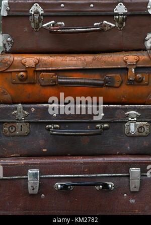 Stack of four old vintage antique grunge travel luggage brown leather suitcase trunks, close up, low angle front view Stock Photo
