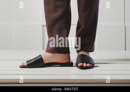 Female legs in leather slippers Stock Photo