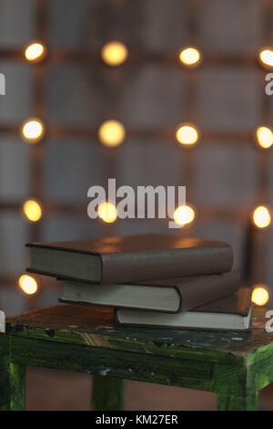 Tree big books on chair near old edison lamp mounted on wooden background Stock Photo