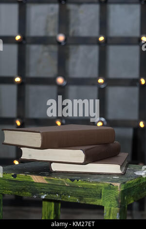 Tree big books on chair near old edison lamp mounted on wooden background Stock Photo