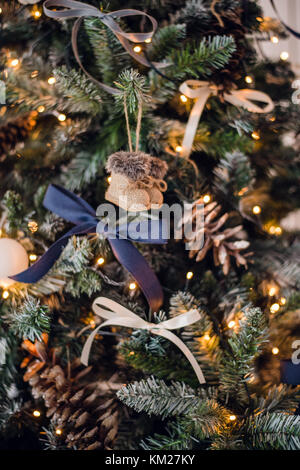 Christmas tree decorations. Toy knitted felt-boots and vintage bows and cones on cristmas tree. Close up shot Stock Photo