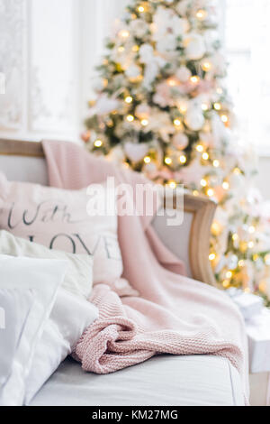 Knitted plaid and pillows on a sofa at home on a christmas eve. Home cosiness Stock Photo