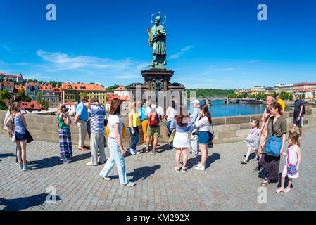 PRAGUE, CZECH REPUBLIC - MAY 28, 2017: Tourists touching a bronze plaque for luck on the St John of Nepomuk statue at Charles bridge. Stock Photo