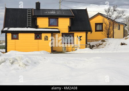 Yellow painted wooden cottages-clapboard siding-vernacular architecture of weatherboards overlapping in horizontal rows-black corrugated gable roof. L Stock Photo