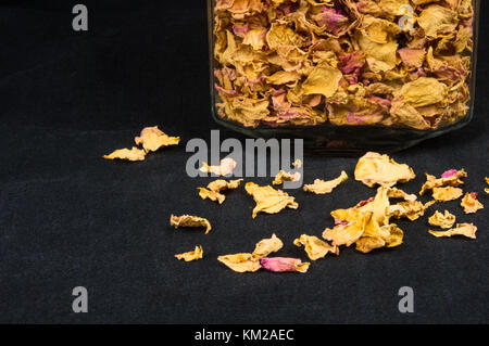 dried rose petals in a glass jar with lid on a black background Stock Photo