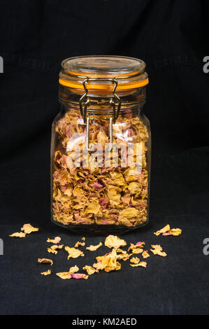 dried rose petals in a glass jar with lid on a black background Stock Photo