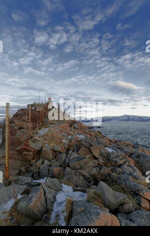 Red roofed small lighthouse on Hjertholmen islet-granite boulders covered breakwater-chain link fence with steel tubing posts-E.boundary of the fishin