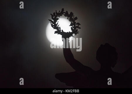 Aberystwyth Wales UK, Sunday 03 December 2017 The 'Supermoon', and extra close and brighter appearance of the full moon, climbs in the sky behind the wreath held in the outstretched hand of the sculpture of the Angel of Peace, on the top of Aberystwyth's distinctive war memorial. Credit: keith morris/Alamy Live News Stock Photo
