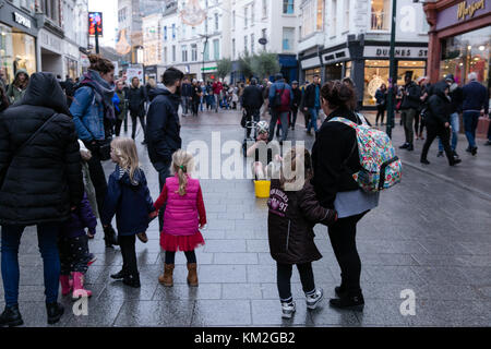 Dublin, Ireland. 3rd Dec, 2017. Family takes a moment away from christmas shopping to watching street perfomer juggling with football on a busy Grafton street. Stock Photo