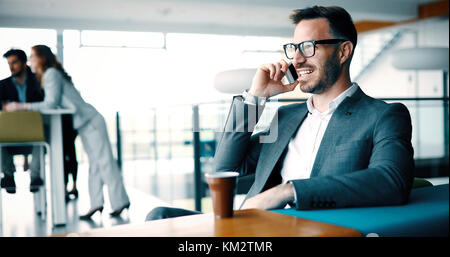 Pensive young businessman in cafe using phone Stock Photo