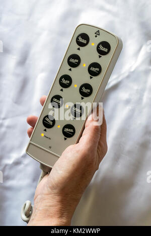 Woman holding the controls for a hospital bed showing the different positions possible. Stock Photo