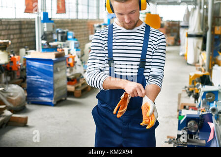 Young Factory Worker Putting On Protective Wear Stock Photo