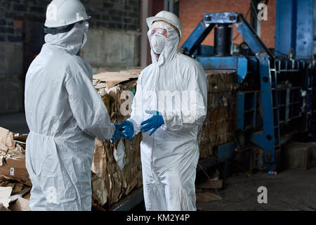 Workers in Hazmat Suits Communicating at Factory Stock Photo