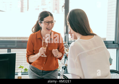three businesswomen enjoy the girls talk in the office and drinking champagne together.